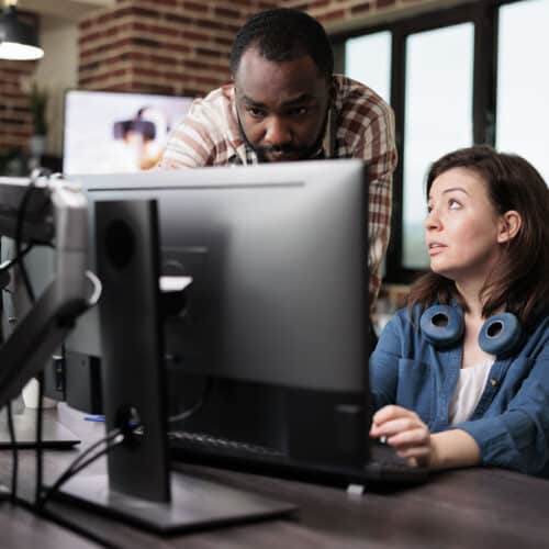 A team collaborating on loan servicing software implementation strategies with laptops and documents on a conference table.